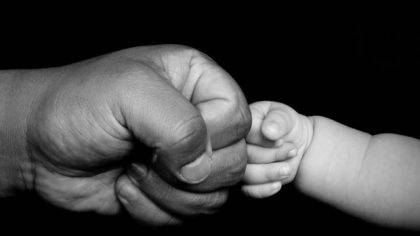 Power of a good man: adult man's hand fist pumping a baby's hand